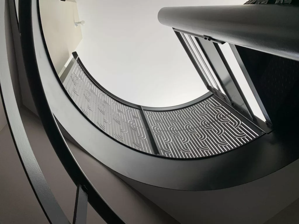 Vue en contre-plongée de l'escalier en colimaçon et de ses panneaux découpés, Villeurbanne