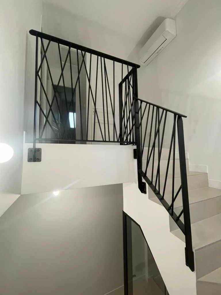 Garde-corps d'escalier à barreaux obliques en acier noir, vue depuis le bas des marches
