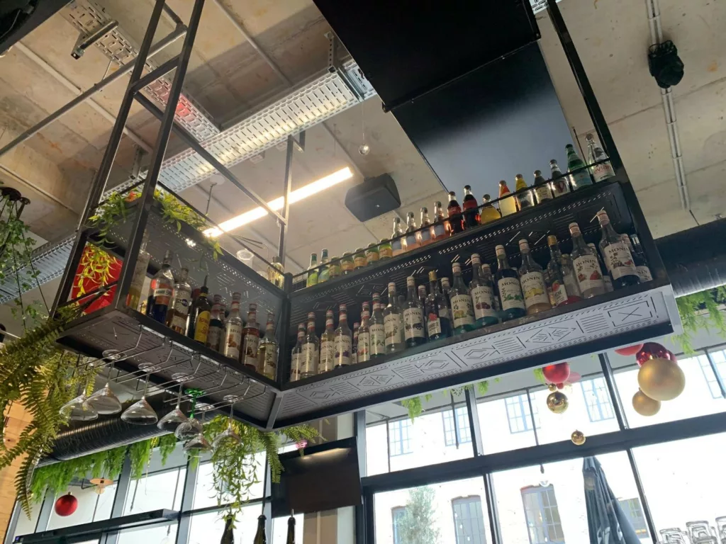 Ciel de bar et étagères à bouteilles suspendues au-dessus du bar du food court Le Beau Marché, Bourg-en-Bresse