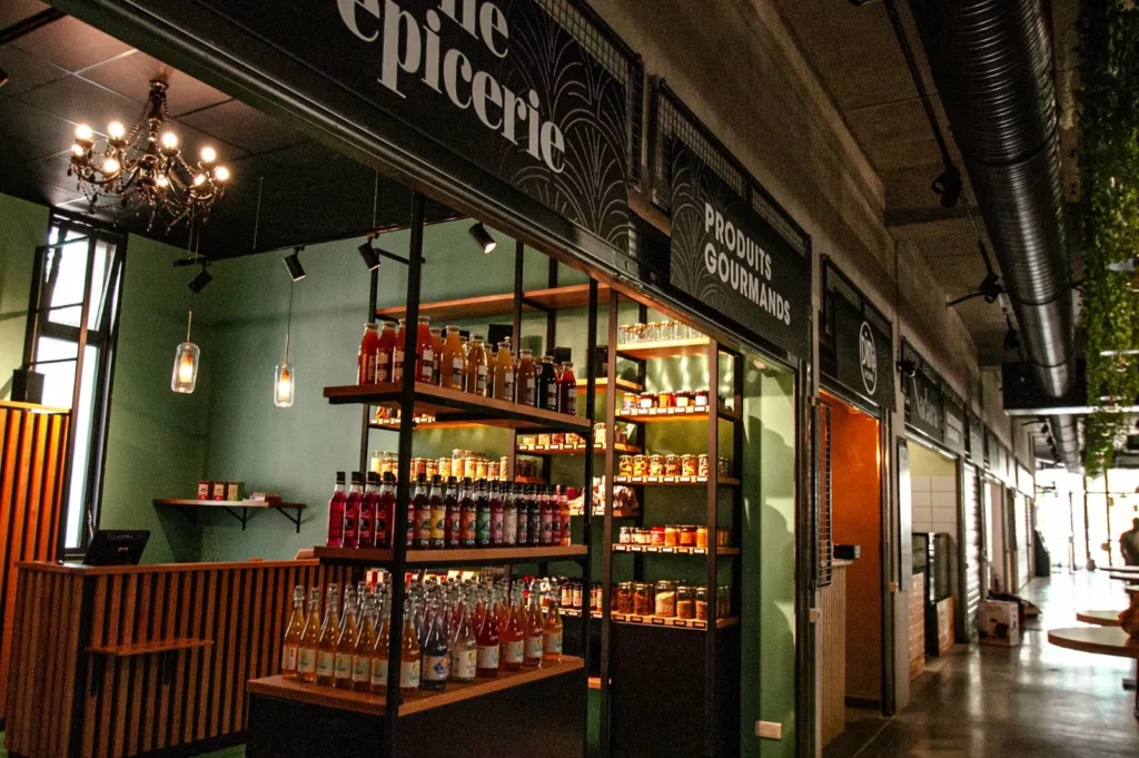 Échoppe épicerie du Beau Marché : agencement bois sur mesure, comptoir cannelé, étagères et enseigne lettrée