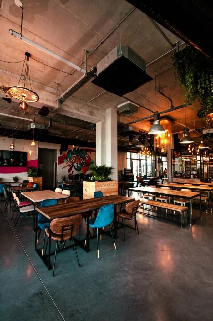 Salle du food court Le Beau Marché avec le bar sur mesure en fond, tables et structure béton apparente