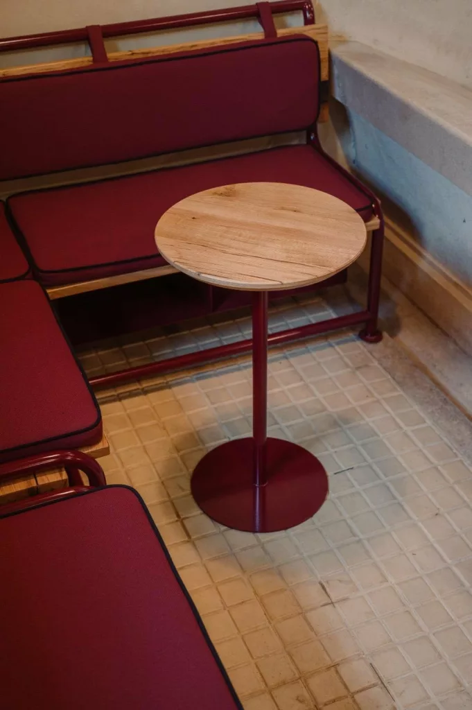 Guéridon à piètement acier et banquette bordeaux, Maison Vermorel