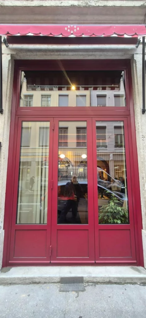 Portes extérieures vitrées en acier thermolaqué rouge du restaurant Sauce Poulette à Lyon, fabriquées par BE PROCESS